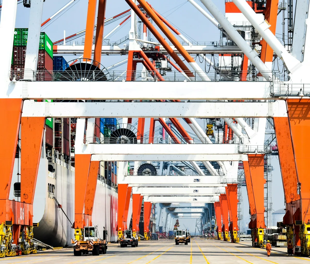 Container ship beside a repeating row of port gantry cranes